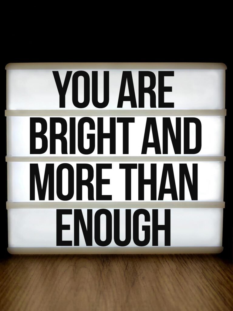Lightbox displaying motivational message 'You are bright and more than enough' on a wooden surface.